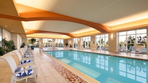 Une grande piscine intérieure dotée de chaises longues et d’une allée dallée.