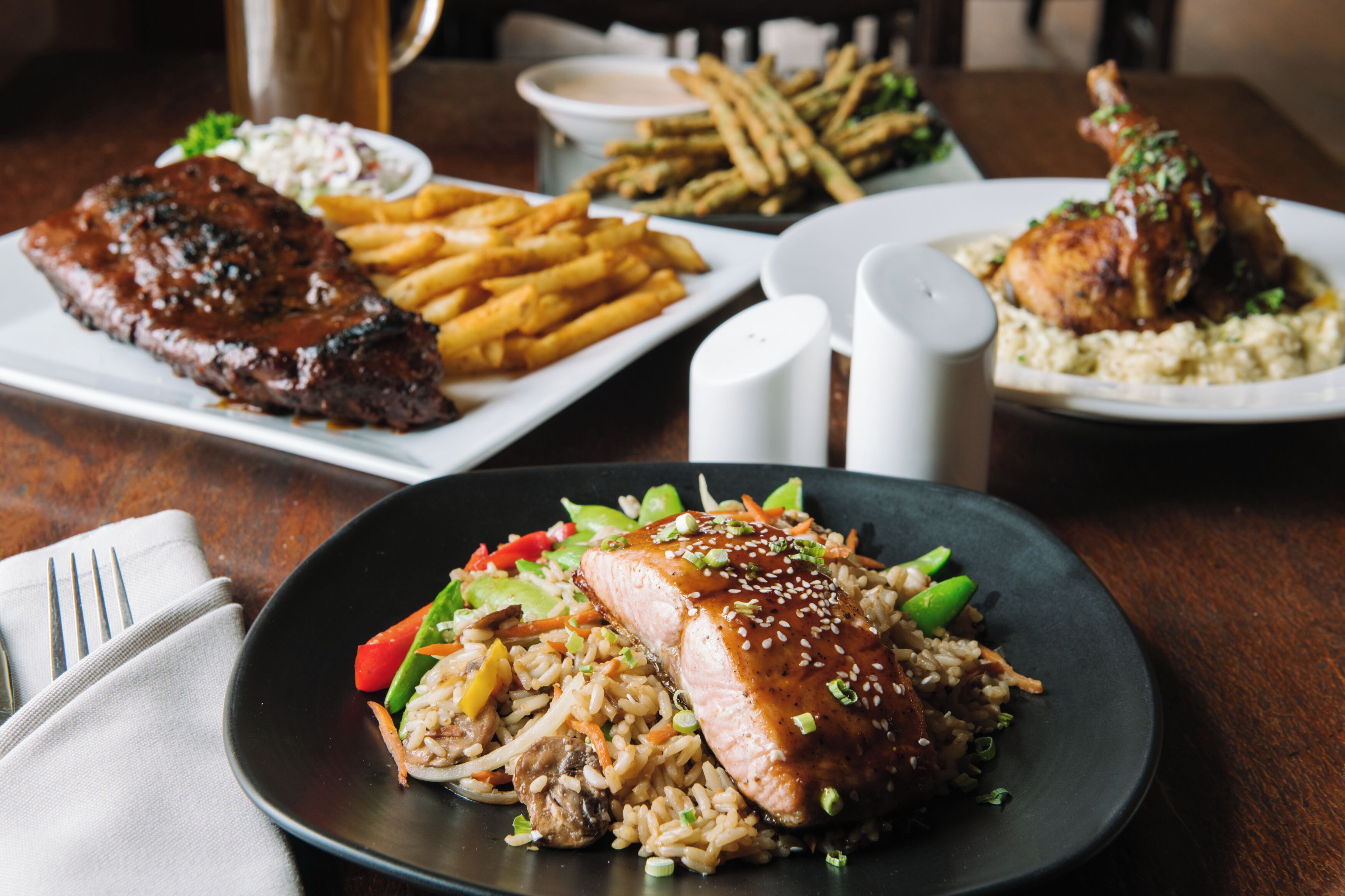 A dining table with various dishes including steak, fries, and rice with vegetables.
