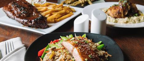 A dining table with various dishes including steak, fries, and rice with vegetables.