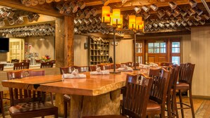 A dining area with a large wooden table and multiple chairs, surrounded by shelves and a television. - The Wolfeboro Inn (Wolfeboro)