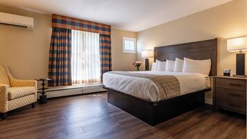 A hotel room with a large bed, a chair, a small table, and a nightstand.