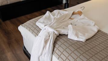 A neatly made bed with a white comforter and a towel draped over the side.