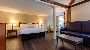 A hotel room with a bed, a sofa, a wooden table, and two bedside lamps.