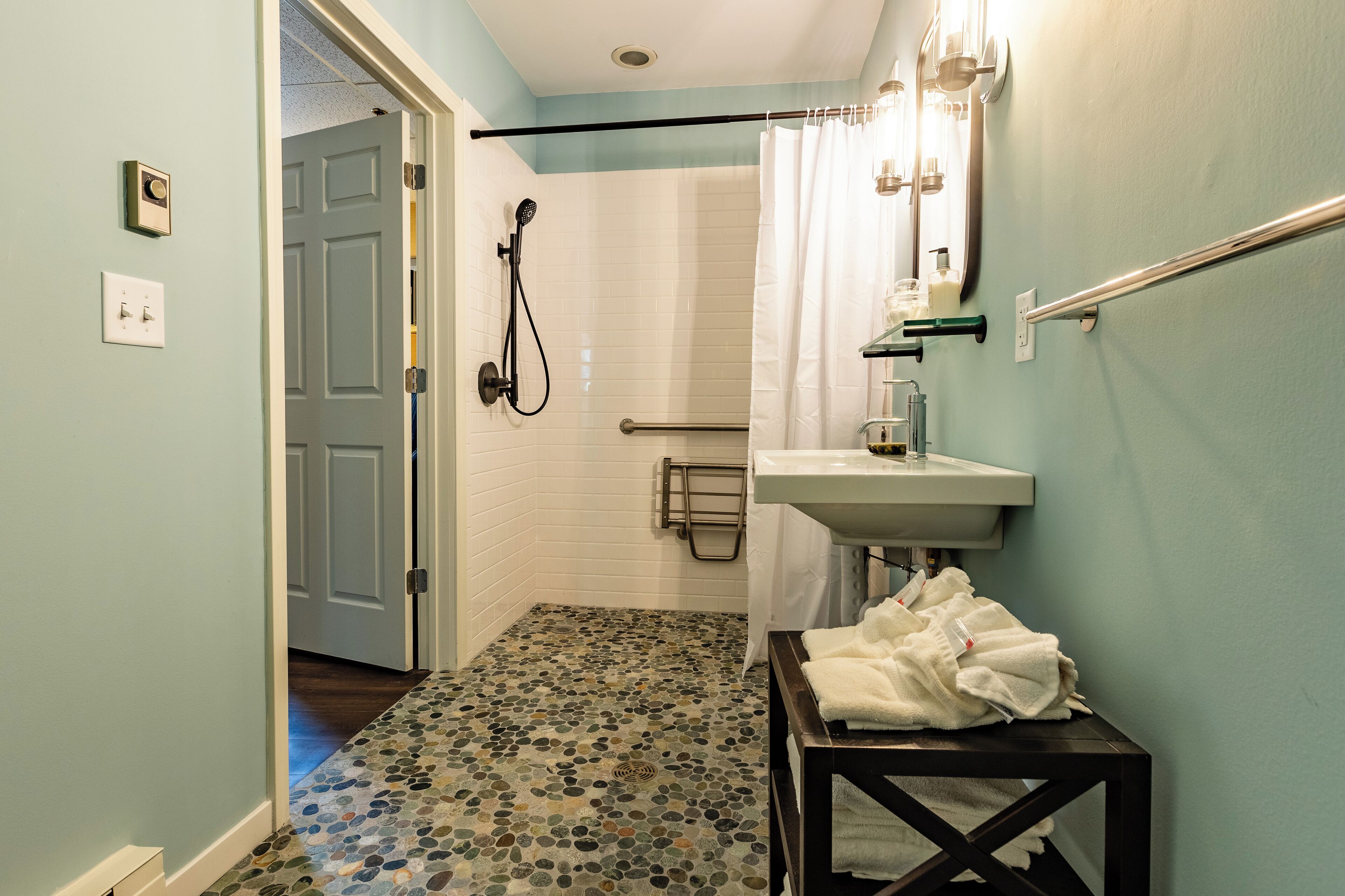 Ein Badezimmer mit Dusche, Waschbecken und Fliesenboden.