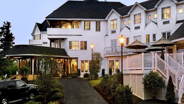 A two-story white building with a covered patio, outdoor seating, and a staircase. - The Wolfeboro Inn (Wolfeboro)