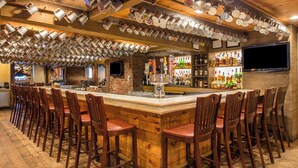 A bar area with a wooden bar counter, multiple stools, and a ceiling adorned with hanging mugs. - The Wolfeboro Inn (Wolfeboro)