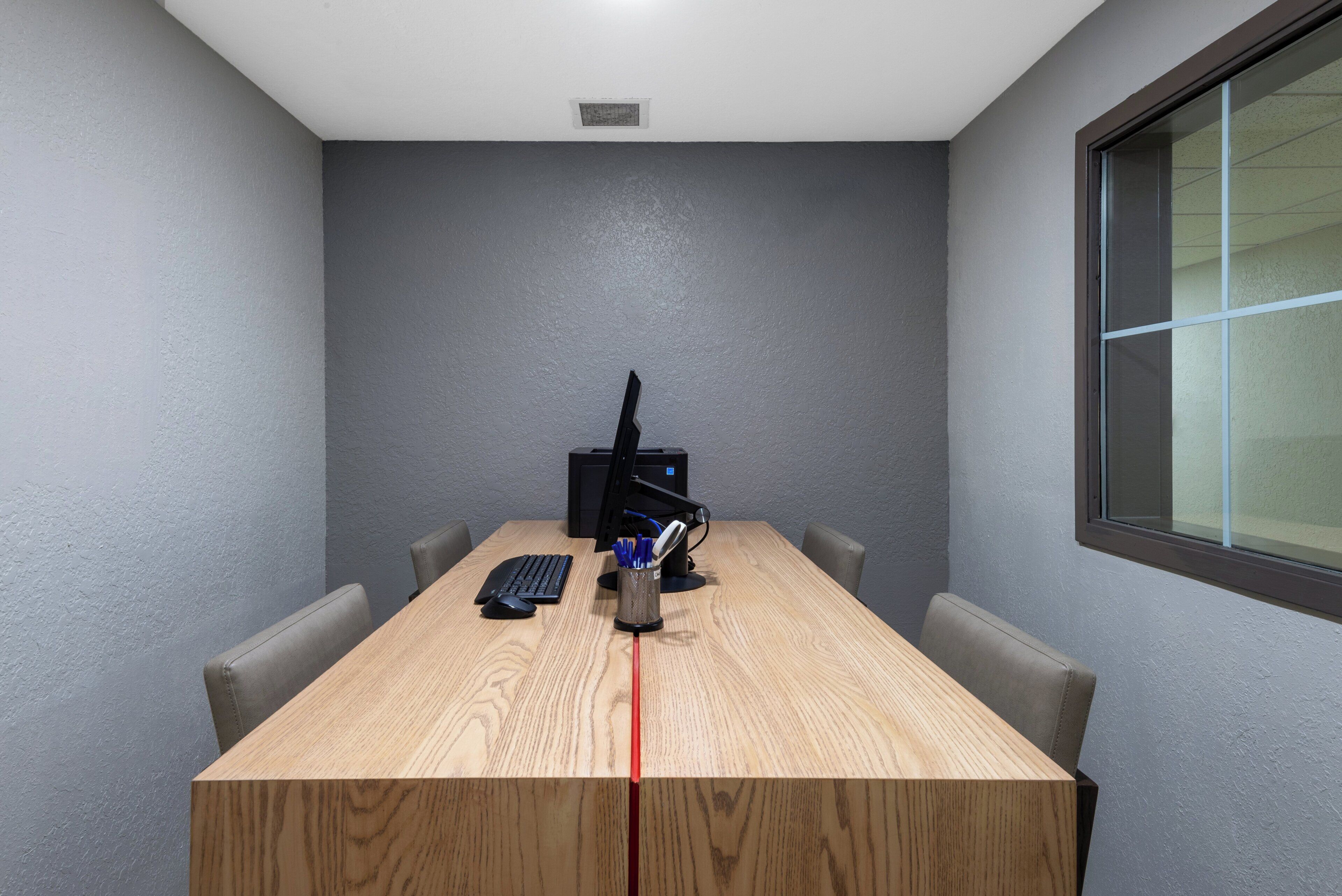 A conference room with a wooden table, a computer, and two chairs.