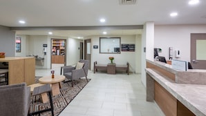 A reception area with a counter, seating, and a coffee machine. - Candlewood Suites Chesapeake/Suffolk by IHG (Chesapeake)