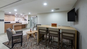 A modern hotel lobby with a reception desk, seating area, and a television mounted on the wall. - Candlewood Suites Chesapeake/Suffolk by IHG (Chesapeake)