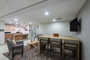 A modern hotel lobby with a reception desk, seating area, and a television mounted on the wall.