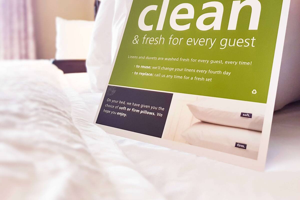 A sign on a bed stating 'clean & fresh for every guest' with details about linen care.
