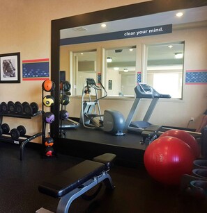 A gym with exercise equipment, a bench, dumbbells, and a red exercise ball. - Hampton Inn & Suites by Hilton Edmonton Intl Airport (Leduc)