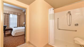 Une chambre d’hôtel équipée d’une douche, d’un lit, d’un bureau et d’une chaise.
