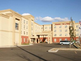 Un hotel Hampton Inn & Suites con entrada principal, varios pisos y un estacionamiento.