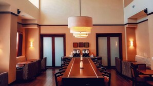 A spacious conference room with a long table, multiple chairs, and a large hanging light fixture. - Hampton Inn & Suites by Hilton Edmonton Intl Airport (Leduc)