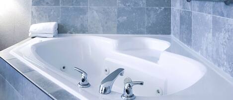 Un baño moderno con una bañera grande, dos grifos y un perchero para toallas.