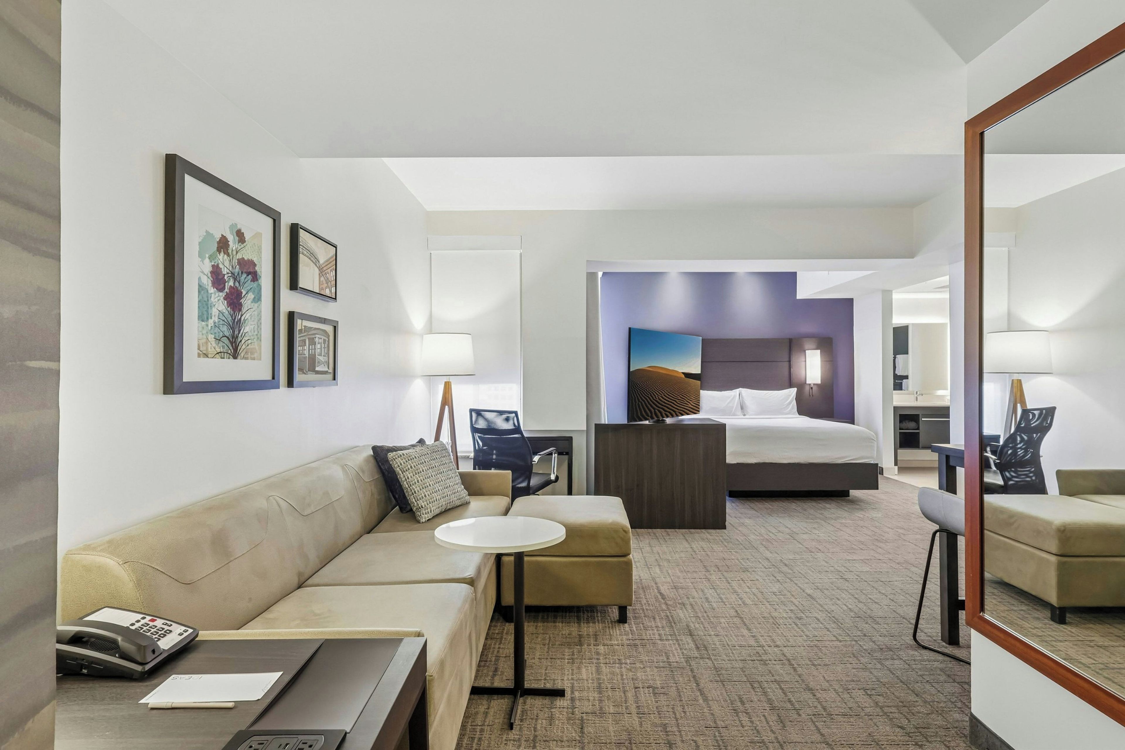 Una habitación de hotel con una cama, un sofá, una mesita y un escritorio con teléfono.