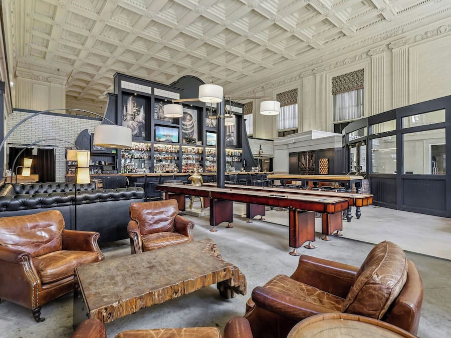 A spacious room with leather seating, a pool table, and a bar area with liquor bottles.