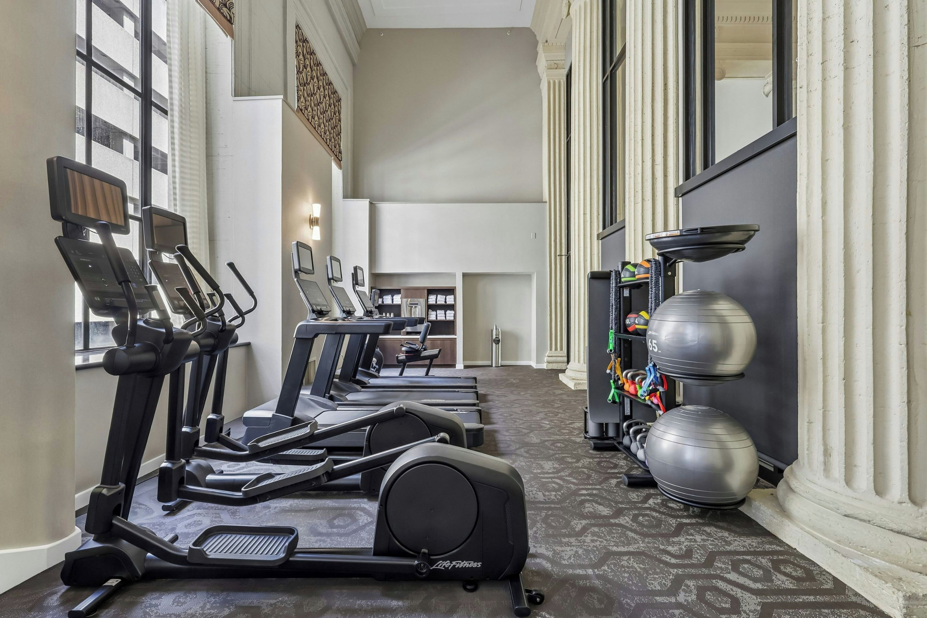 A gym with treadmills, a weight bench, and exercise balls.