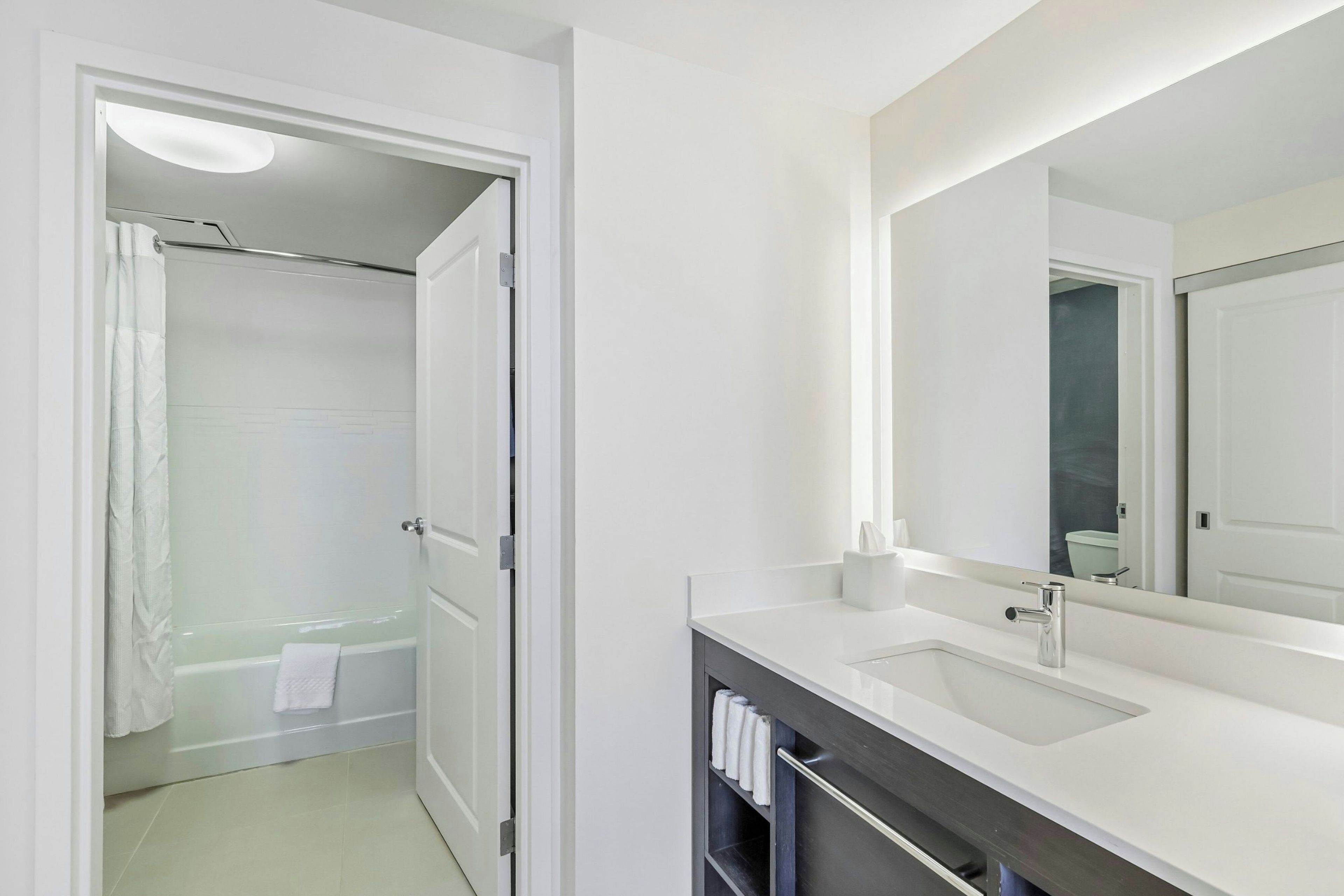 Un baño moderno con un lavamanos blanco, un espejo y una zona de ducha.