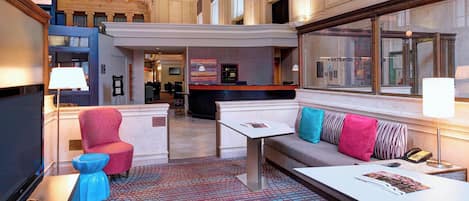 A lobby with a reception desk, seating area, and a patterned carpet.