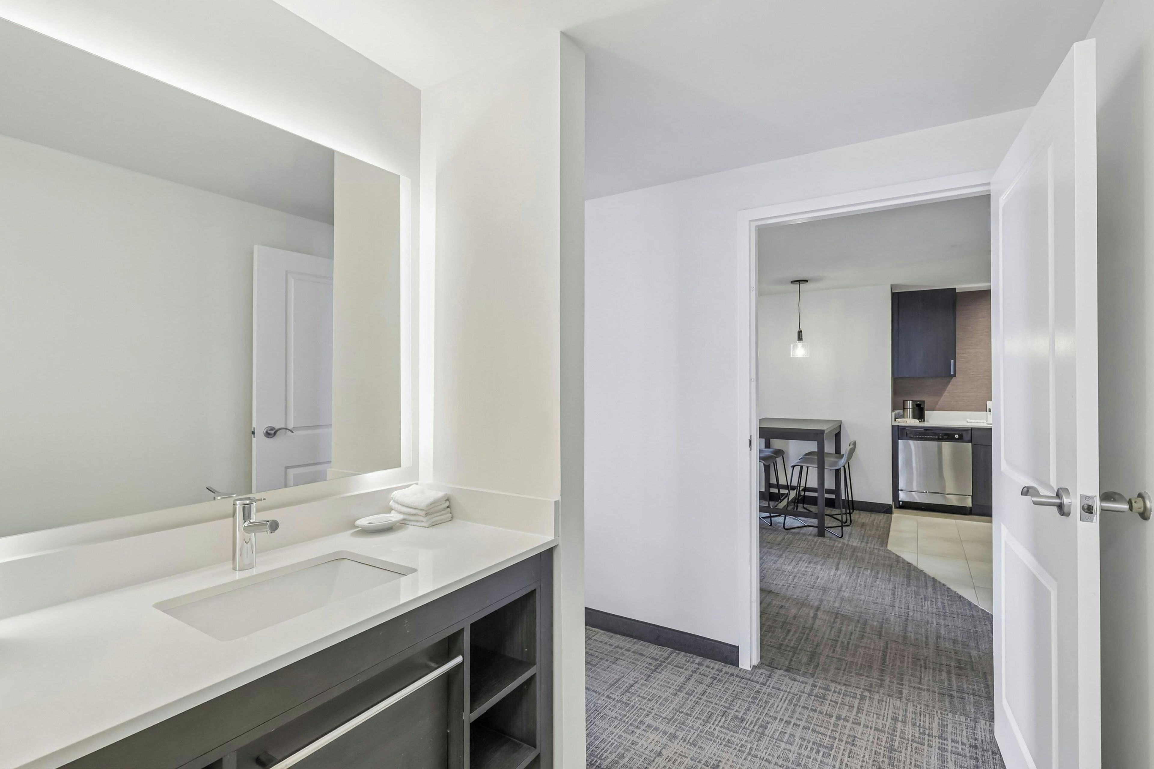Un baño moderno con un espejo grande, un lavamanos y un perchero para toallas.