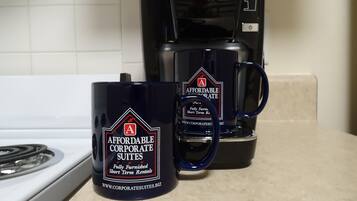 Two coffee mugs with "AFFORDABLE CORPORATE SUITES" branding on a kitchen counter.
