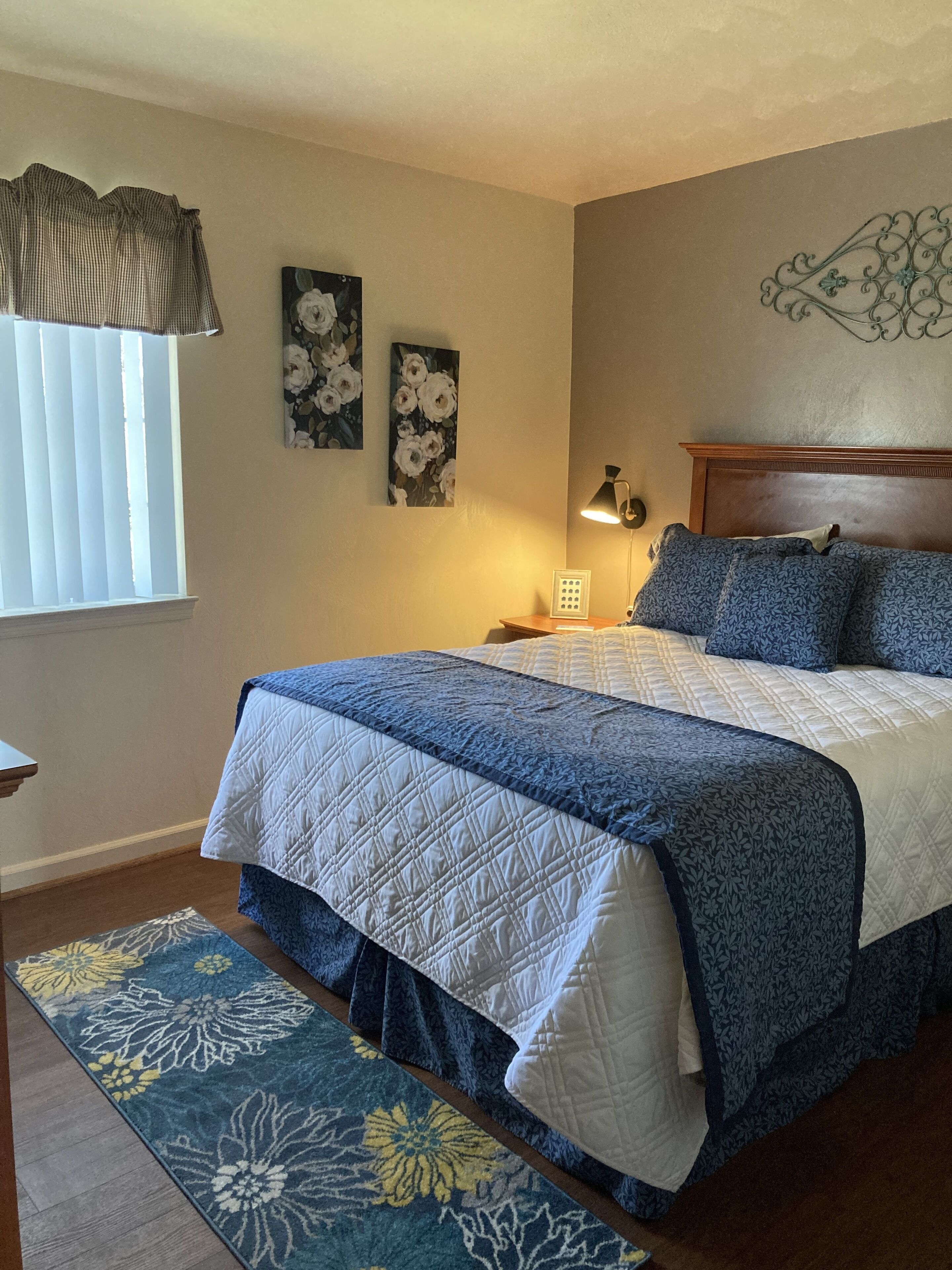A bedroom with a bed, a nightstand, a lamp, and a window with blinds.