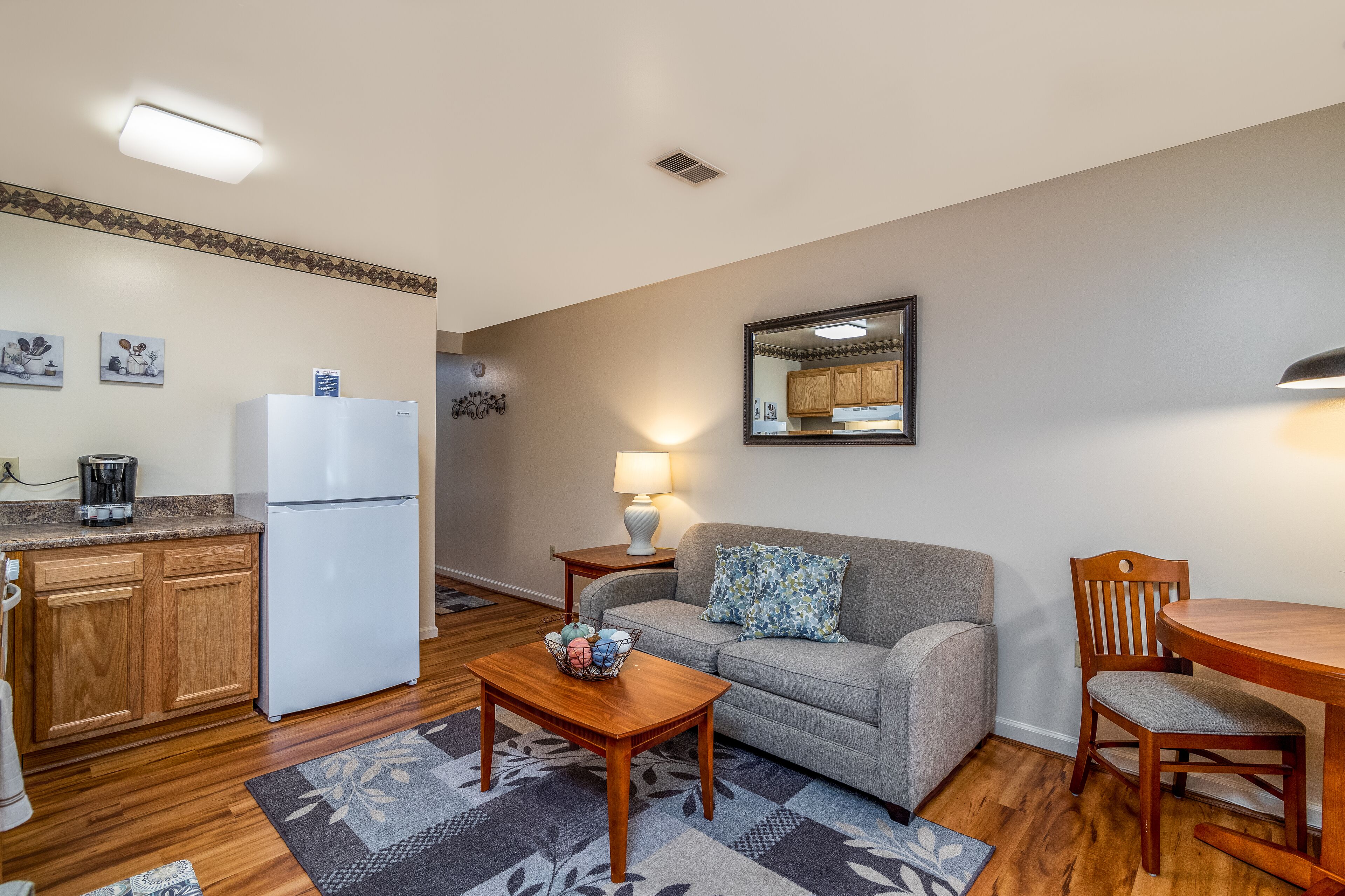 A compact living space with a kitchenette, a sofa, a dining table, and a coffee maker.