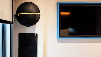 A black speaker and a flat-screen TV mounted on a wall.