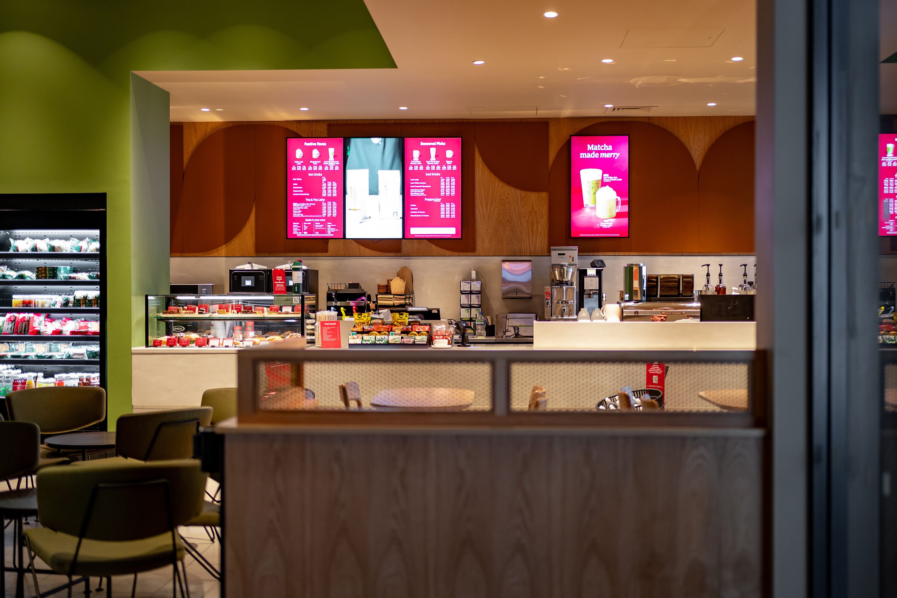 Un café moderne avec un comptoir, des panneaux affichant le menu et un espace pour s’asseoir.