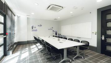 A conference room with a long table, chairs, a whiteboard, and motivational posters on the walls.