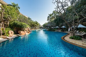 A swimming pool with clear blue water, surrounded by lush greenery and palm trees.