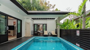 A modern indoor swimming pool with a tiled floor, a no diving sign, and a seating area with chairs and a table.