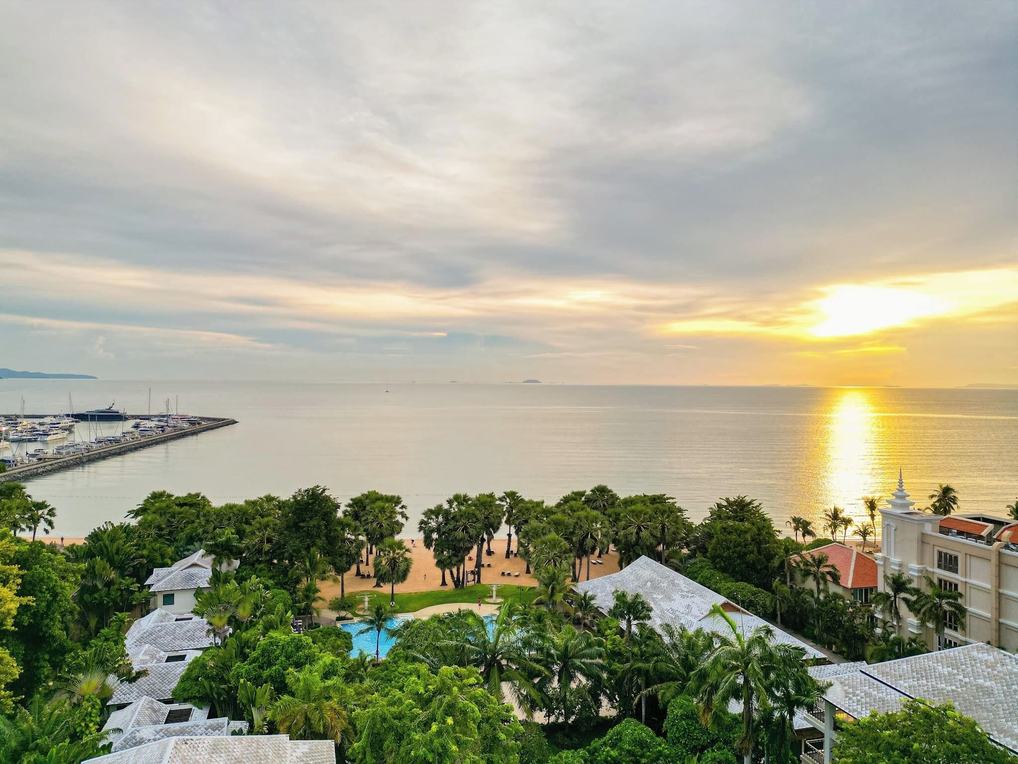 A coastal resort with a marina, swimming pool, and lush greenery.