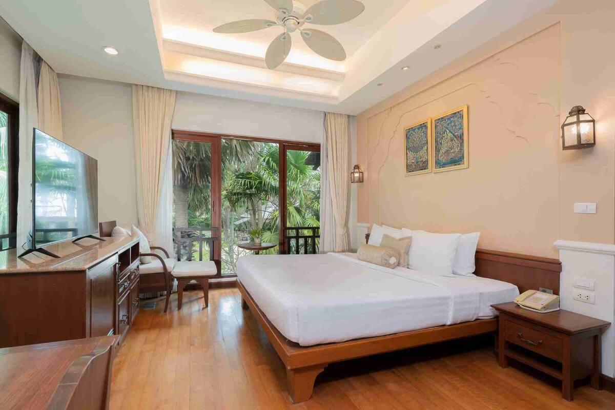 Quarto de hotel com cama, escrivaninha, cadeira e vista para o exterior.