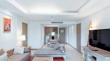 A modern living room with a sofa, a coffee table, and a TV stand. There is a kitchen area in the background.