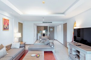 A modern living room with a sofa, a coffee table, and a TV stand. There is a kitchen area in the background.