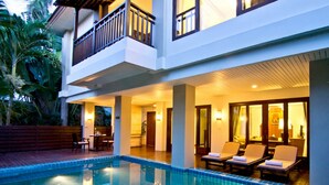 A hotel with a swimming pool, lounge chairs, and a balcony.