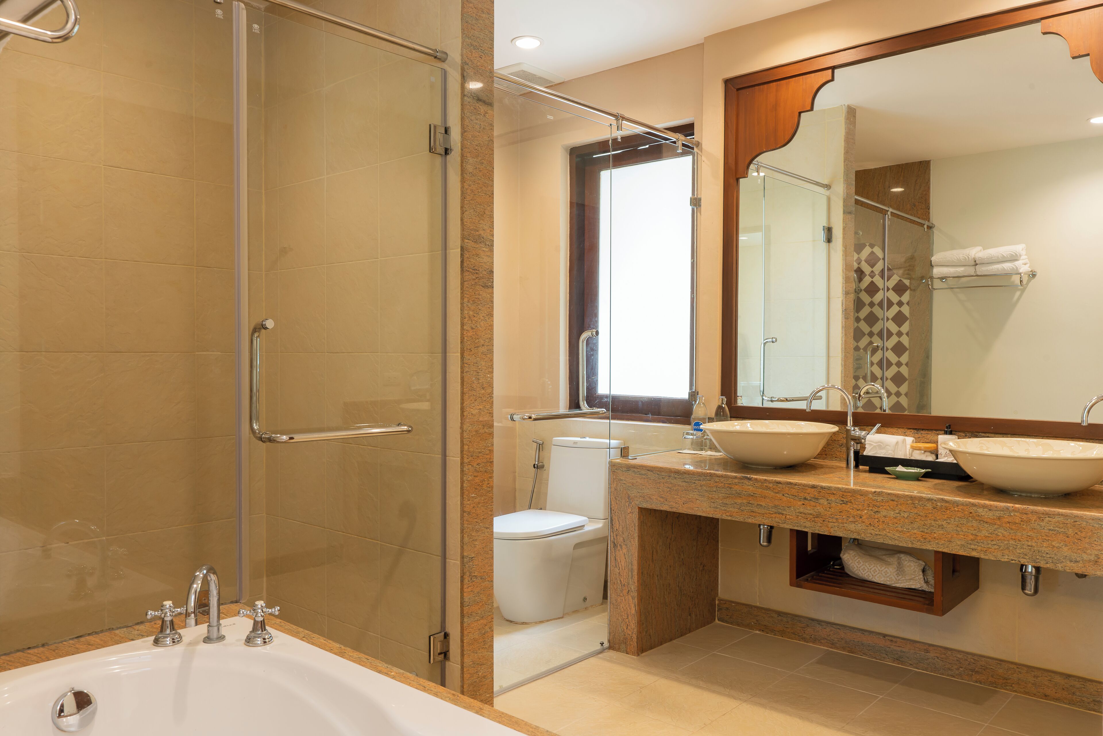 A modern bathroom with a glass-enclosed shower, a double sink vanity, and a toilet.