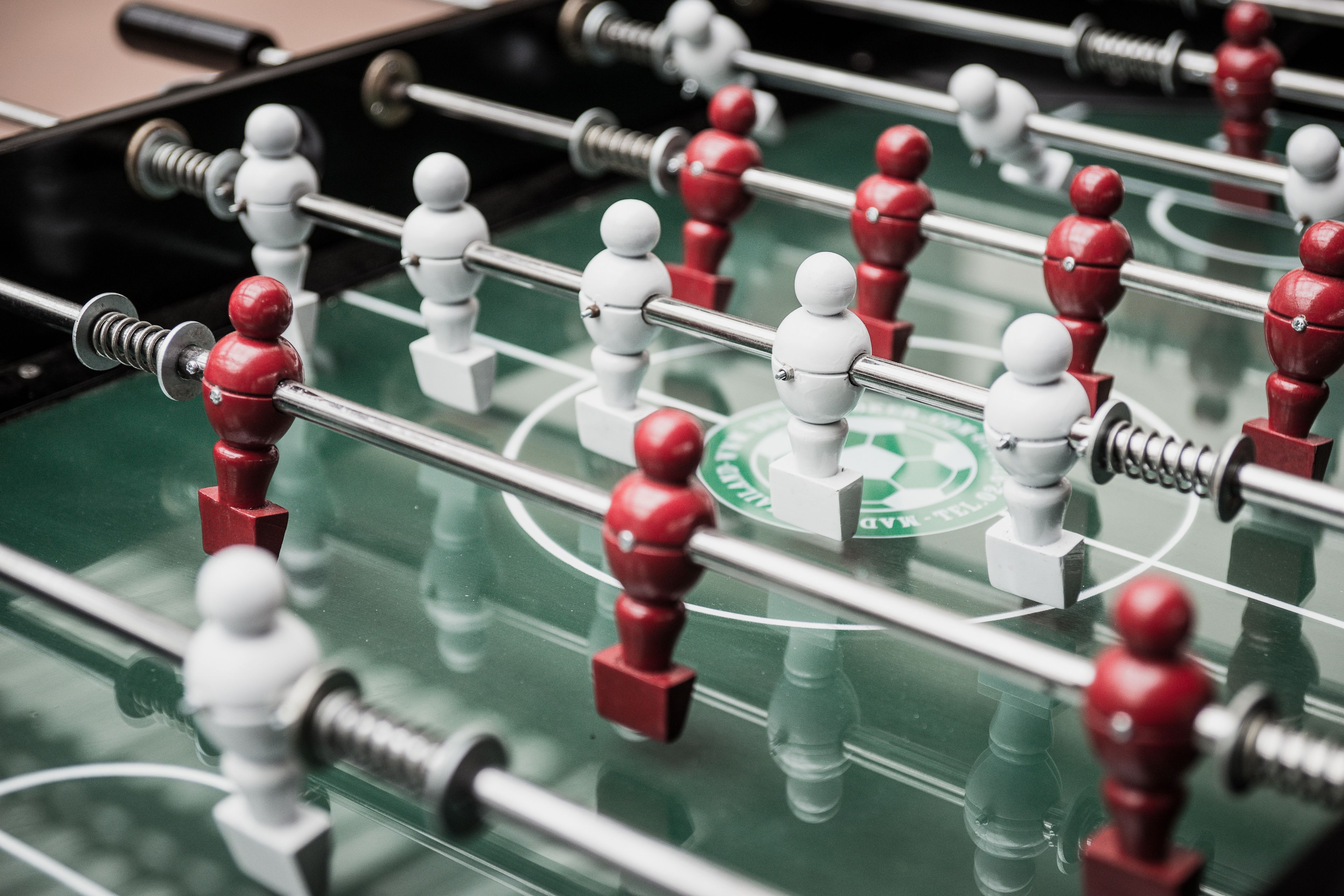 A close-up of a foosball table with red and white figures.