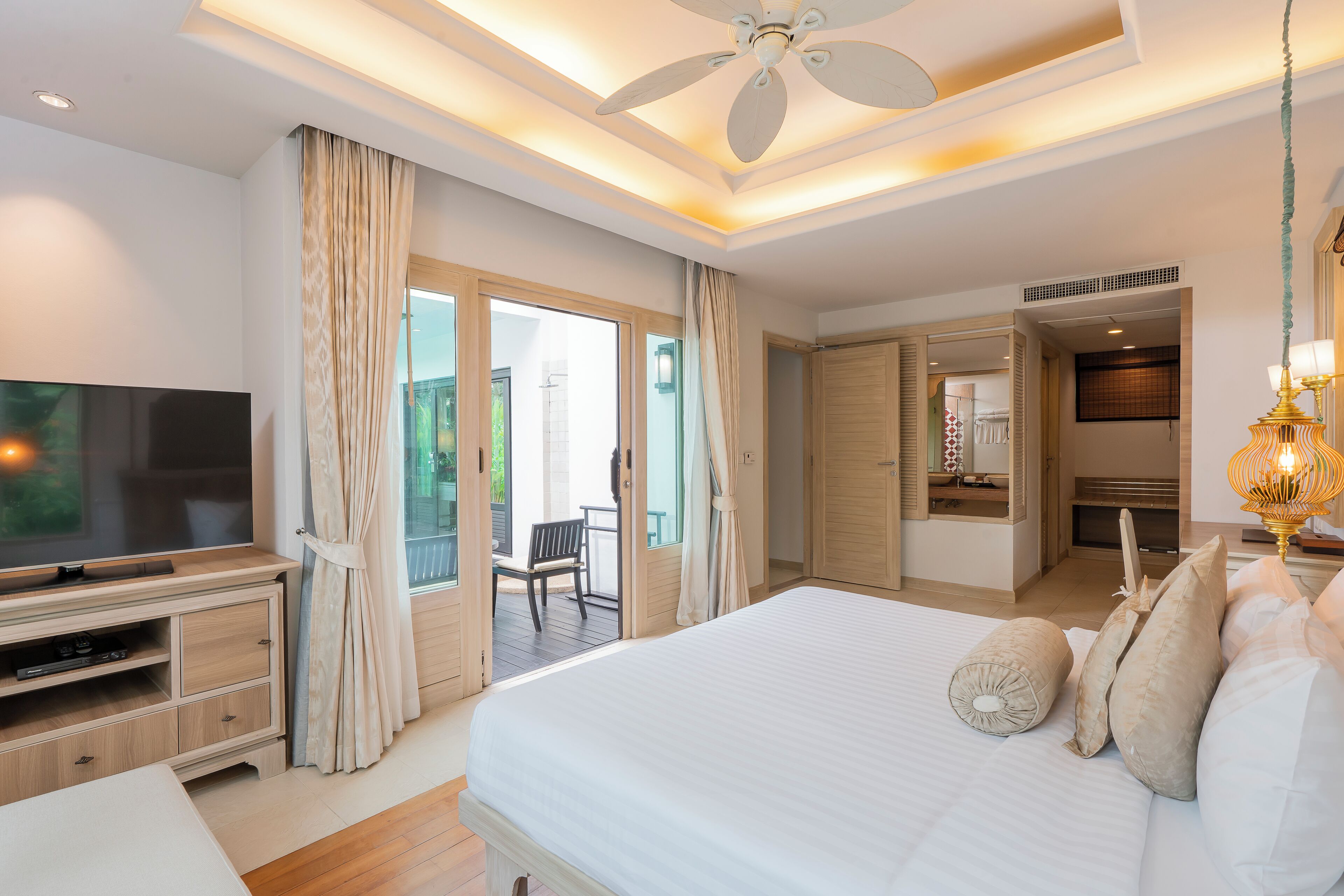 A modern bedroom with a large bed, a TV, and a balcony.