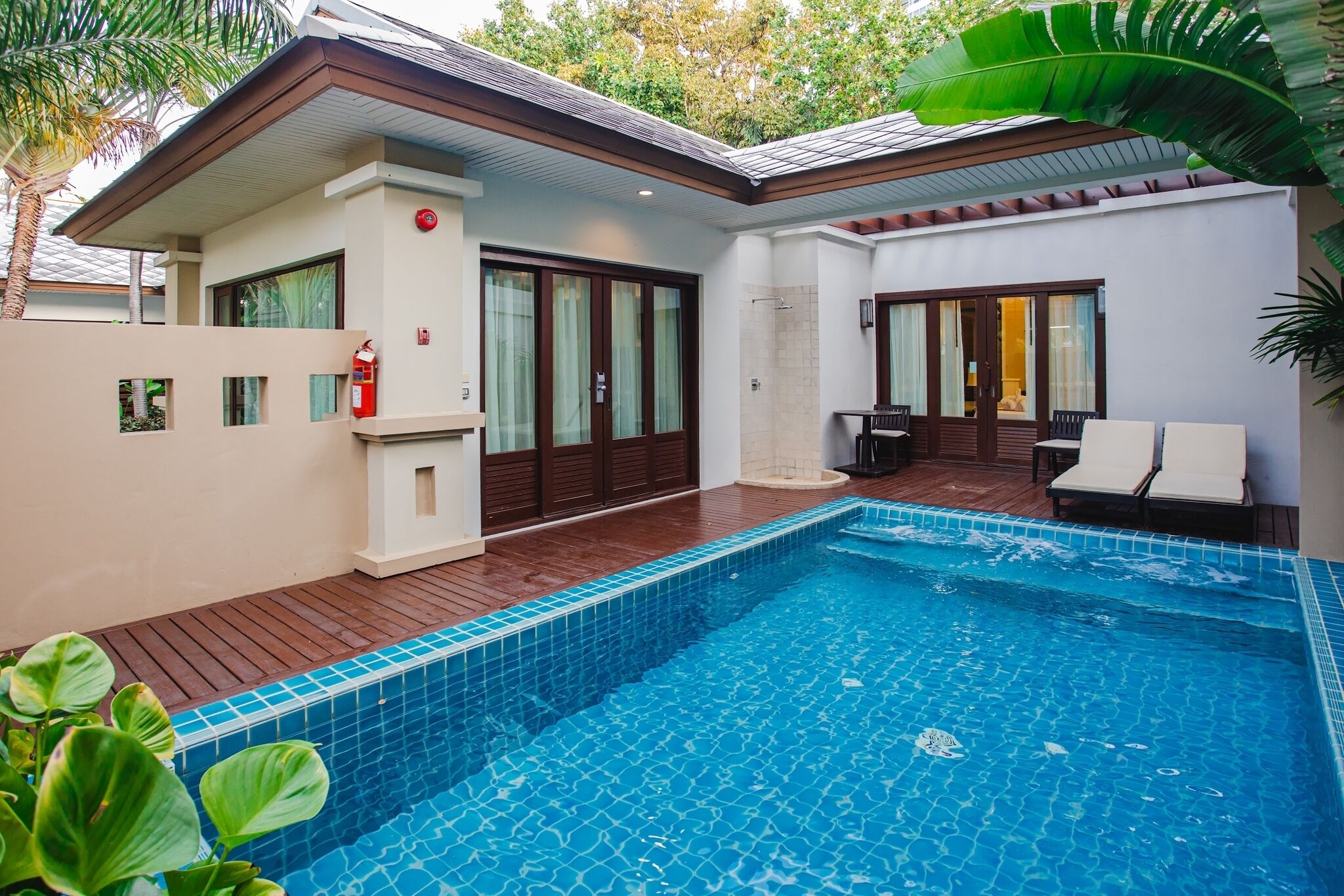 A modern house with a swimming pool, wooden deck, and a covered patio area.