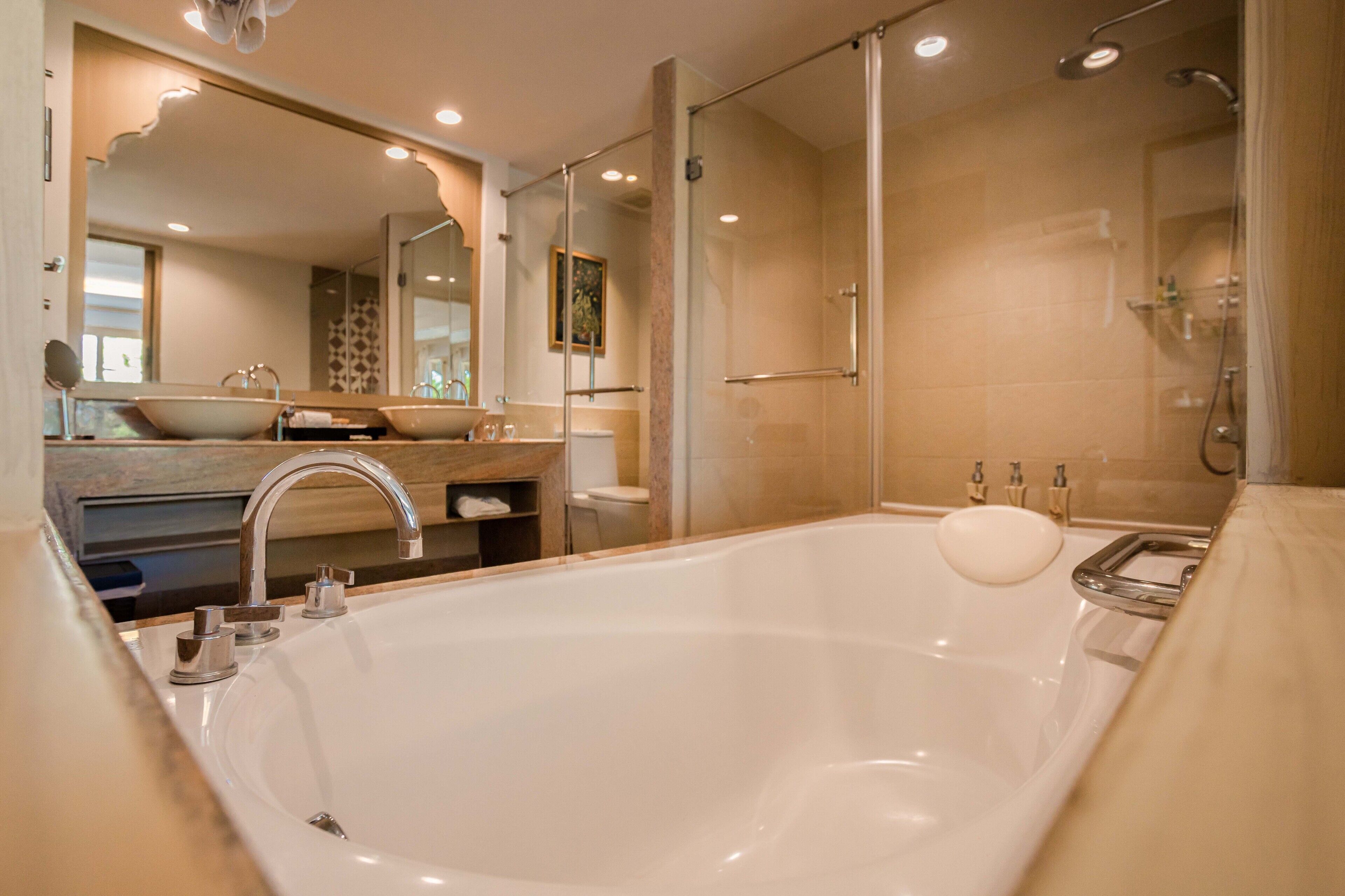 A modern bathroom with a large bathtub, a double sink vanity, and a glass-enclosed shower area.