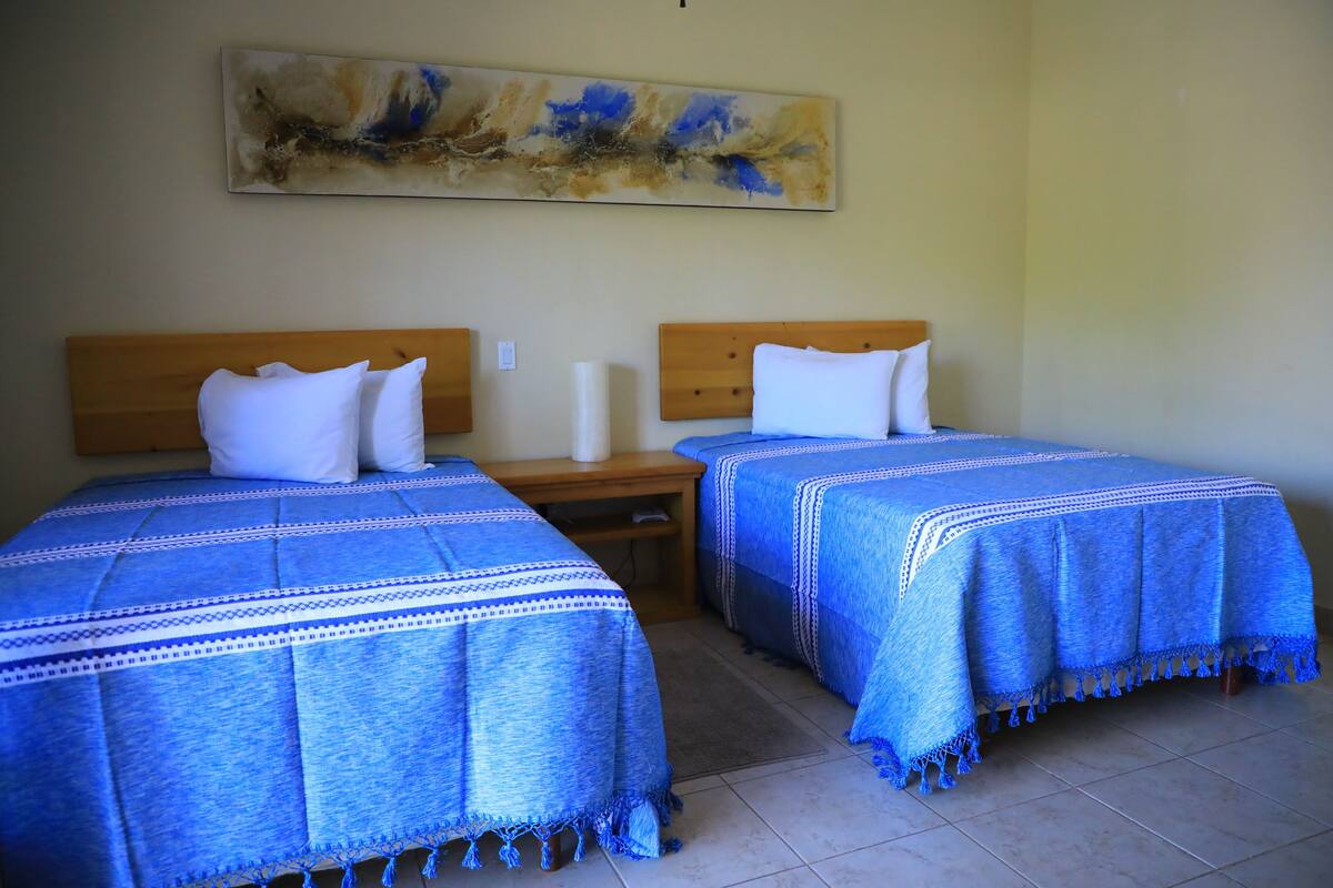 Two single beds with wooden headboards, a nightstand between them, and a painting on the wall.