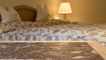 Una cama con ropa de cama floral, un cabecero de madera y una mesita de noche con una lámpara.