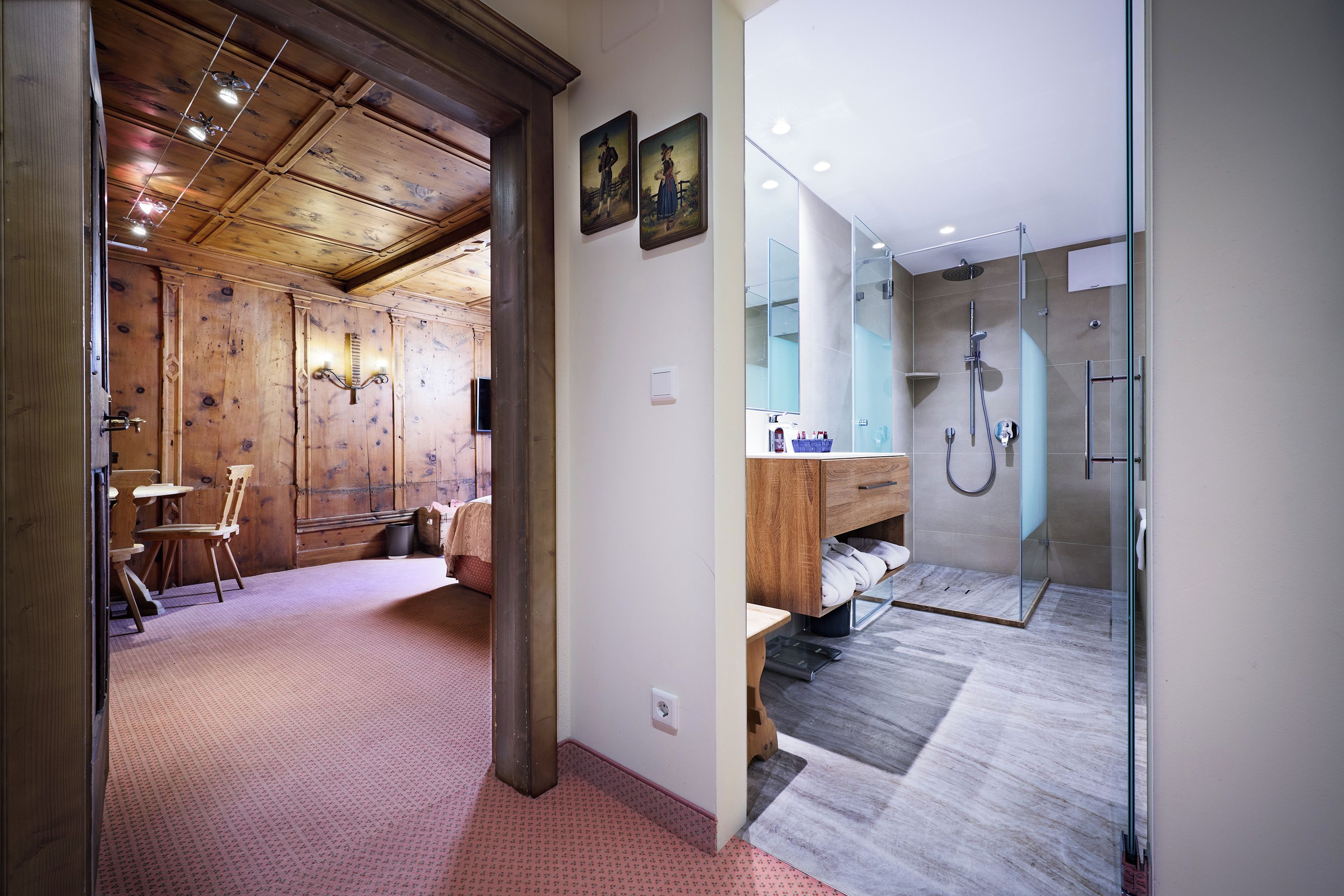 Un baño moderno con cabina de ducha de vidrio, suelo de madera y tocador de madera.