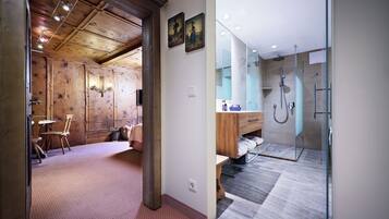 Un baño moderno con cabina de ducha de vidrio, suelo de madera y tocador de madera.
