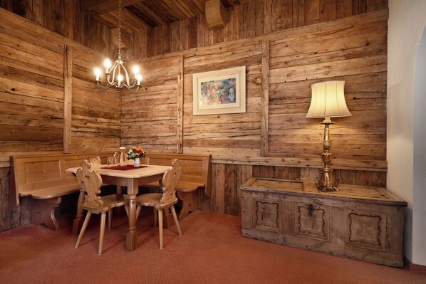 Una habitación rústica de madera con una mesa de comedor, sillas, una araña, un cuadro enmarcado y una lámpara.