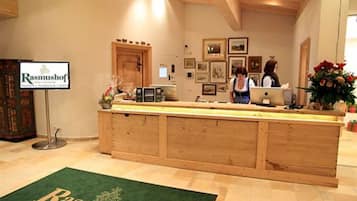 A reception area with a wooden counter, framed pictures on the wall, and a sign that reads "Rasmushof Golf & Ski Resort".